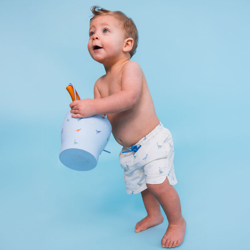 Baby holding a toy bucket against a blue background