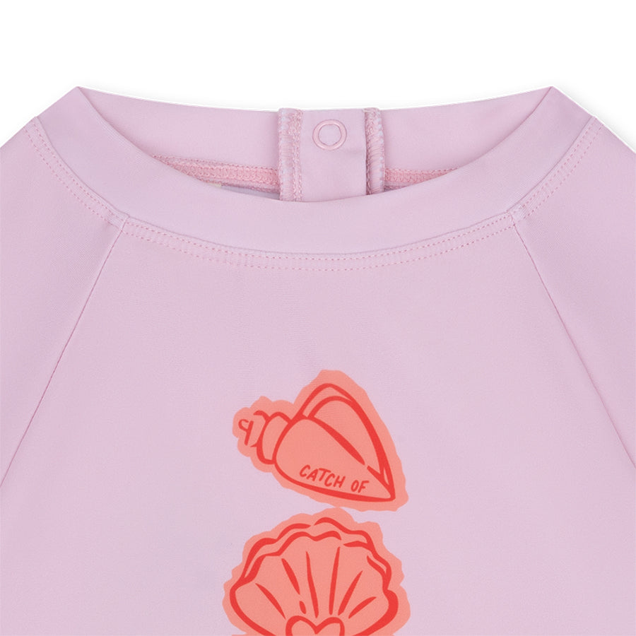 Pink garment with shell designs and text on a white background