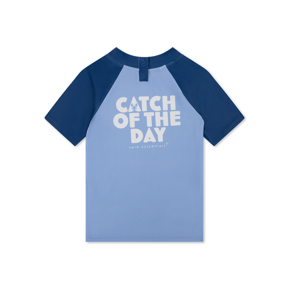 Blue and navy swim shirt with 'Catch of the Day' text on a white background