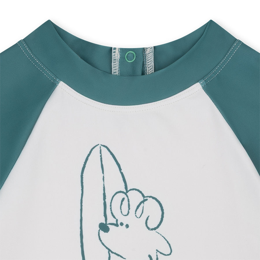 Close-up of a children's shirt with teal sleeves and collar, featuring a cartoon character on a white background.