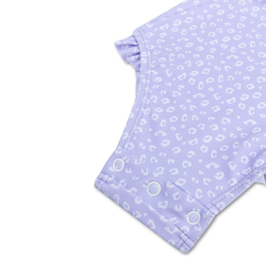 Detail of the press stud fastening on the purple leopard swimsuit against a white background.