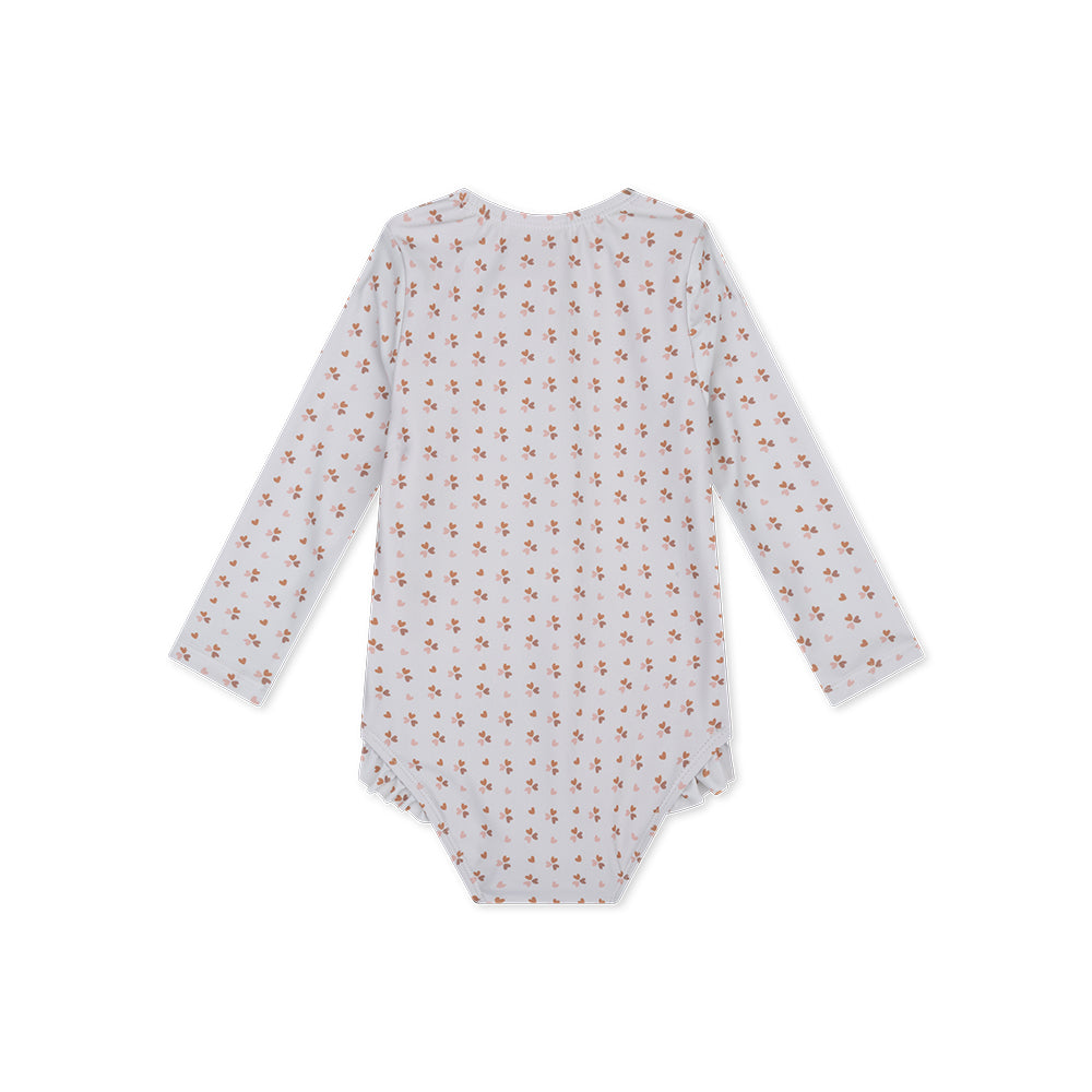 The back of the old pink cozy hearts-patterned long-sleeve swimsuit, with ruffles on a white background