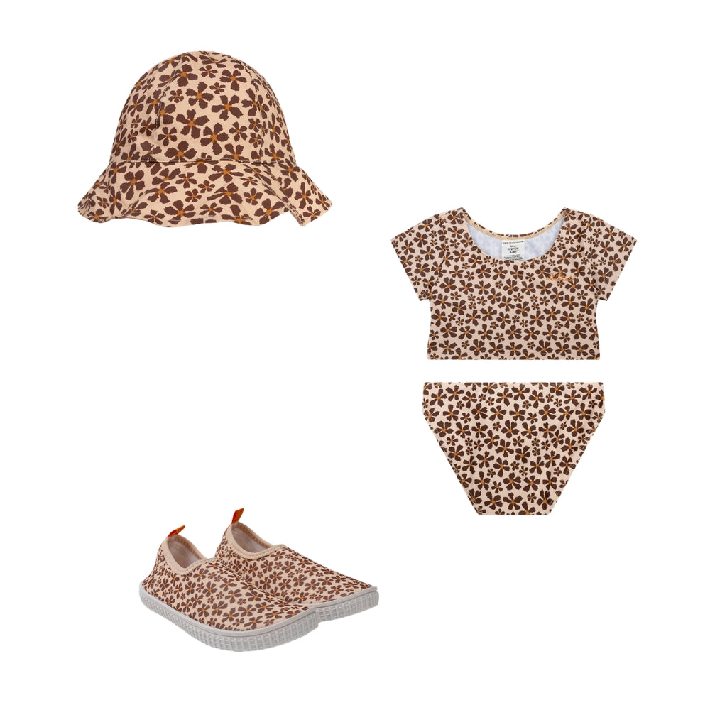 This is a set comprising a beach hat, a bikini and water shoes featuring the ‘Wild Flower’ print.  The beach hat is decorated with brown flowers with orange centres. The bikini has a longer top, so that part of the child’s tummy remains covered. This bikini also features the print with brown flowers and orange centres. The shoes have a white sole and are likewise decorated with brown flowers with orange centres. This is featured on a white background.