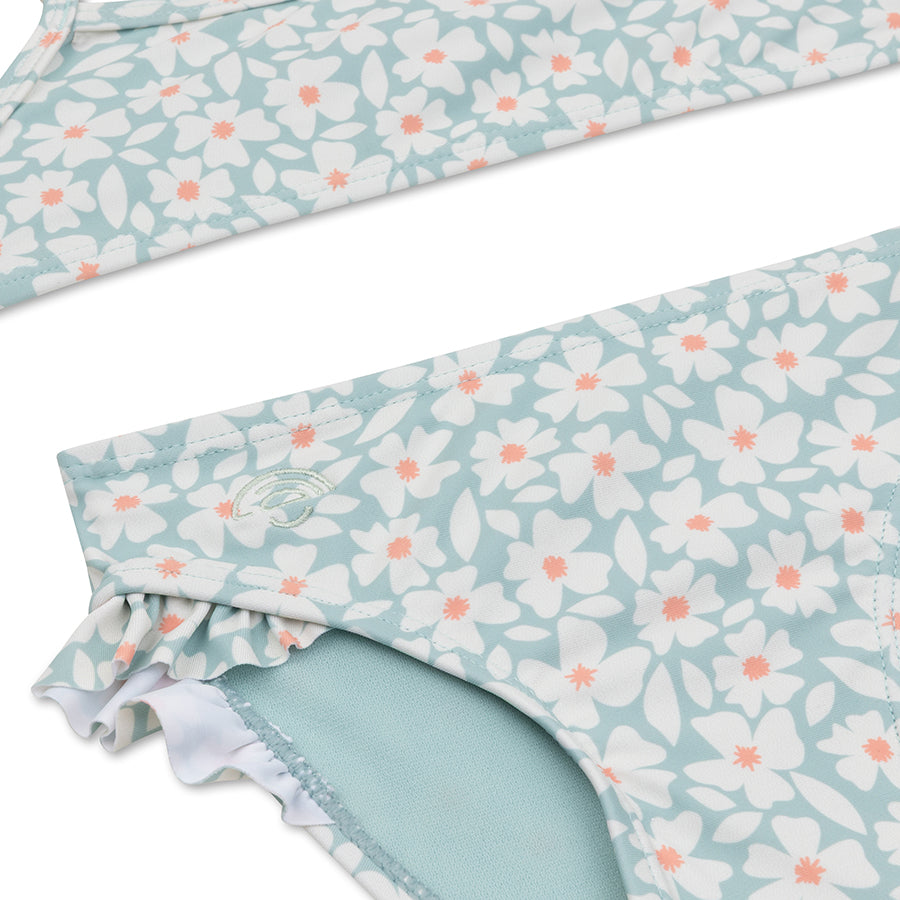 Close-up of a floral-patterned bikini with white flowers and pink centers on a white background