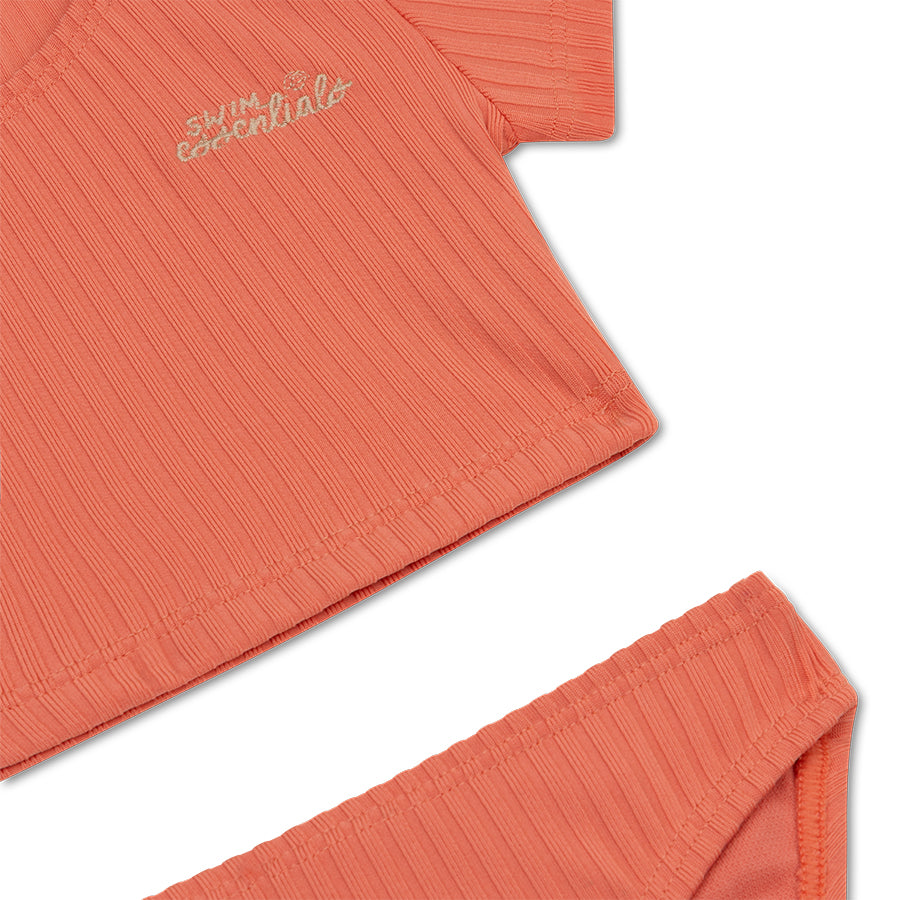 Coral-colored bikin with 'swim essentials' embroidery on a white background