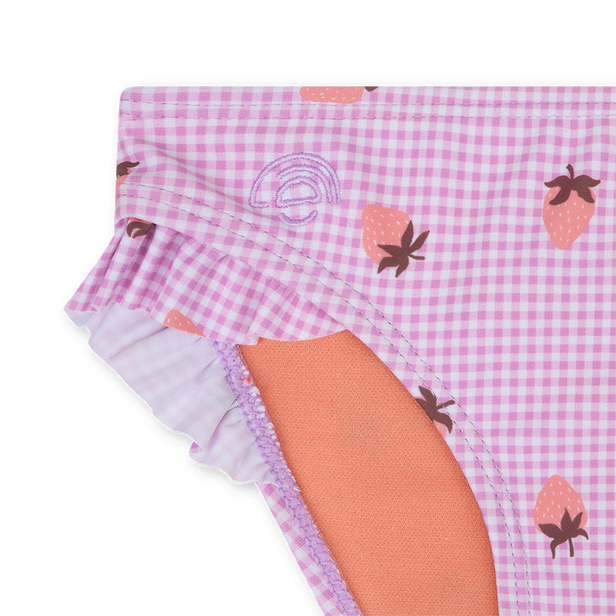 Close-up of a pink checkerd bikini with a strawberry print on a white background