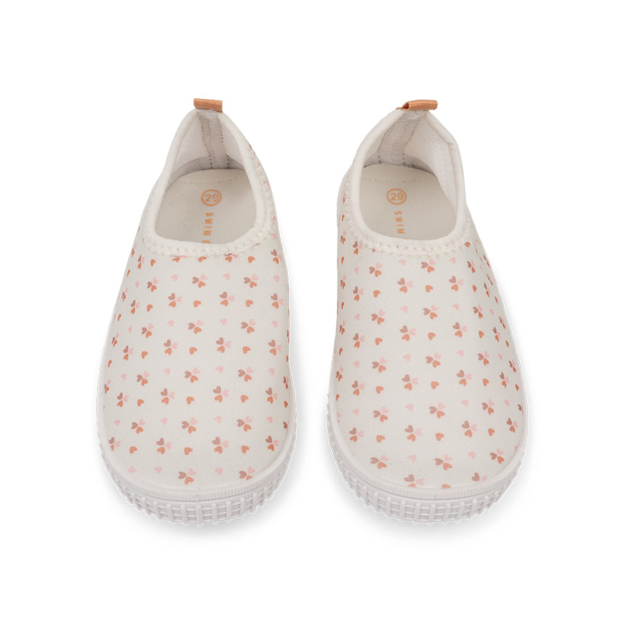 Pair of white slip-on water shoes with small floral pattern on a white background