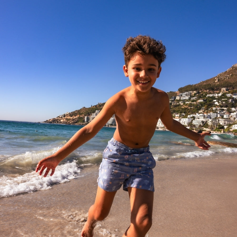 Child running on a beach with ocean and town in the background