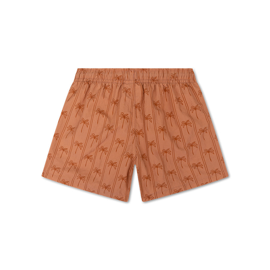 The back of boys swim shorts. They are brown and feature stripes and palm trees. There is also a white background. 