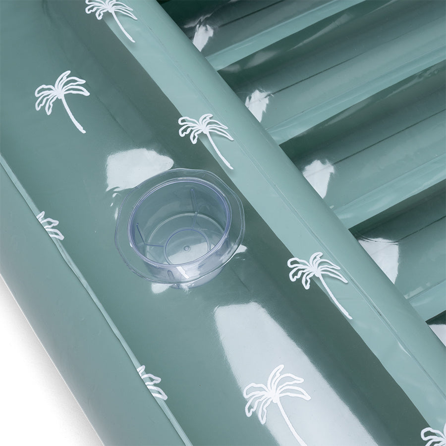 Transparent cup holder in a green tanning bed with white palm tree motifs
