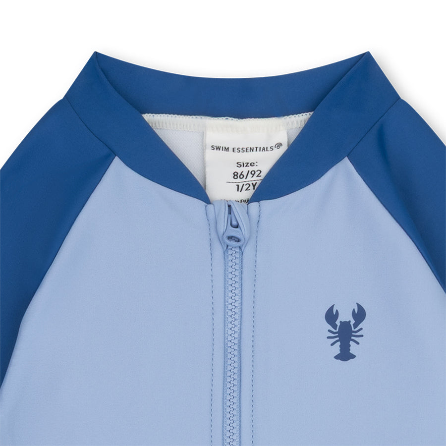 Close-up of a blue and gray children's swimsuit with a lobster logo and brand label.
