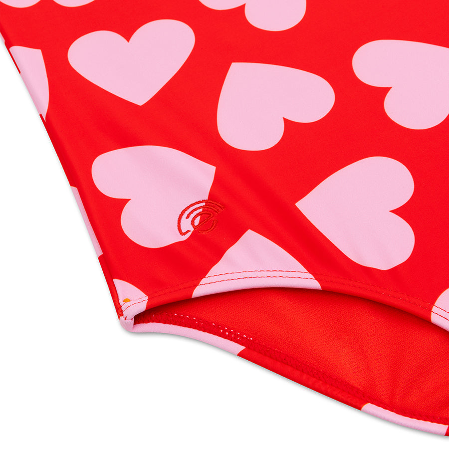 Red swimsuit detail picture with pink heart patterns on a white background