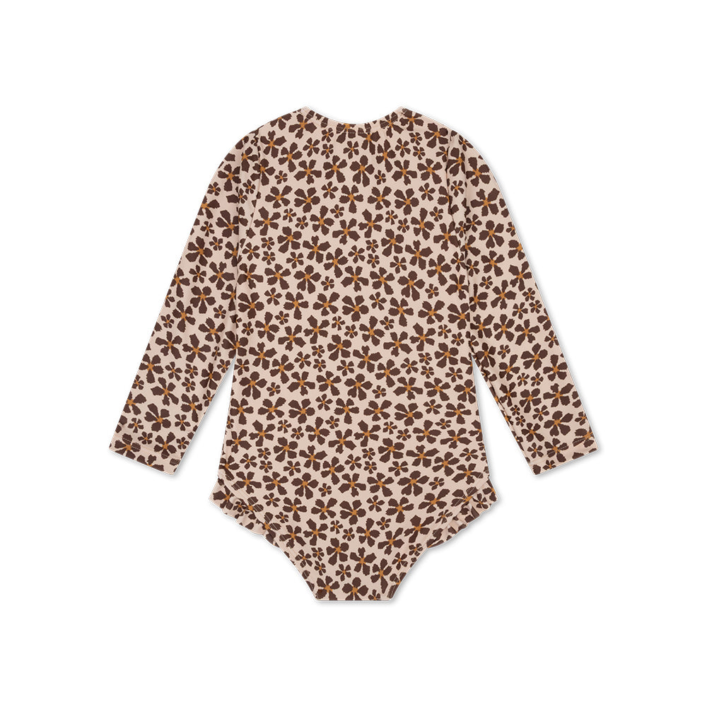 The back of a girls swimsuit with long sleeves, and ruffles with a wild flower pattern with orange in the middle on a white background.