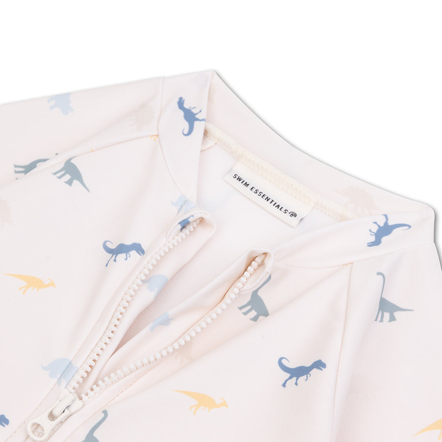 Close-up of the white swimsuit with blue and yellow dinosaur prints, featuring the Swim Essentials label on a white background.
