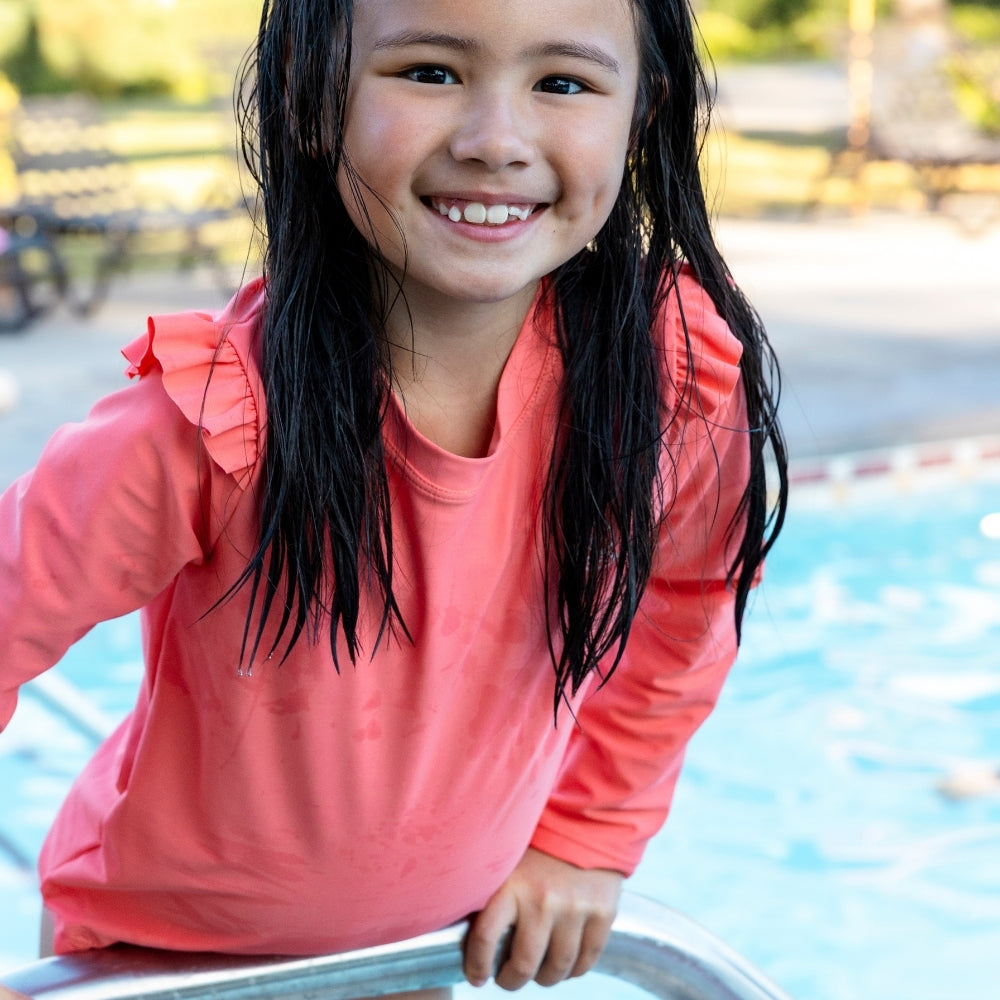 Young girl in a pink shirt by a pool